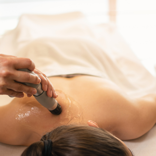 Shockwave therapy device being pressed against a painful neck muscle